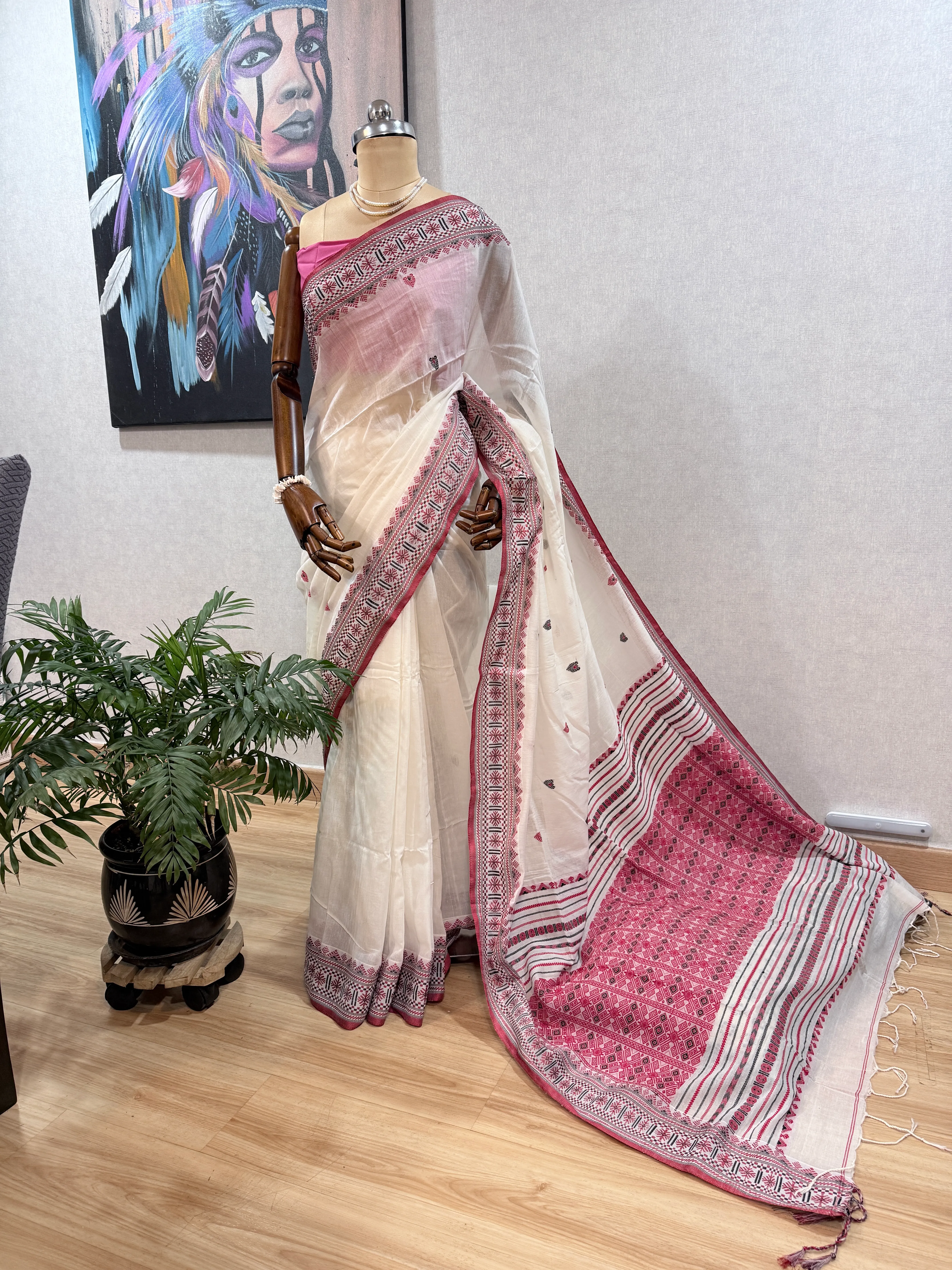 Dhonekhali cotton saree draped on a mannequin, pallu spread out showing the pink-and-black striped and diamond border pattern.