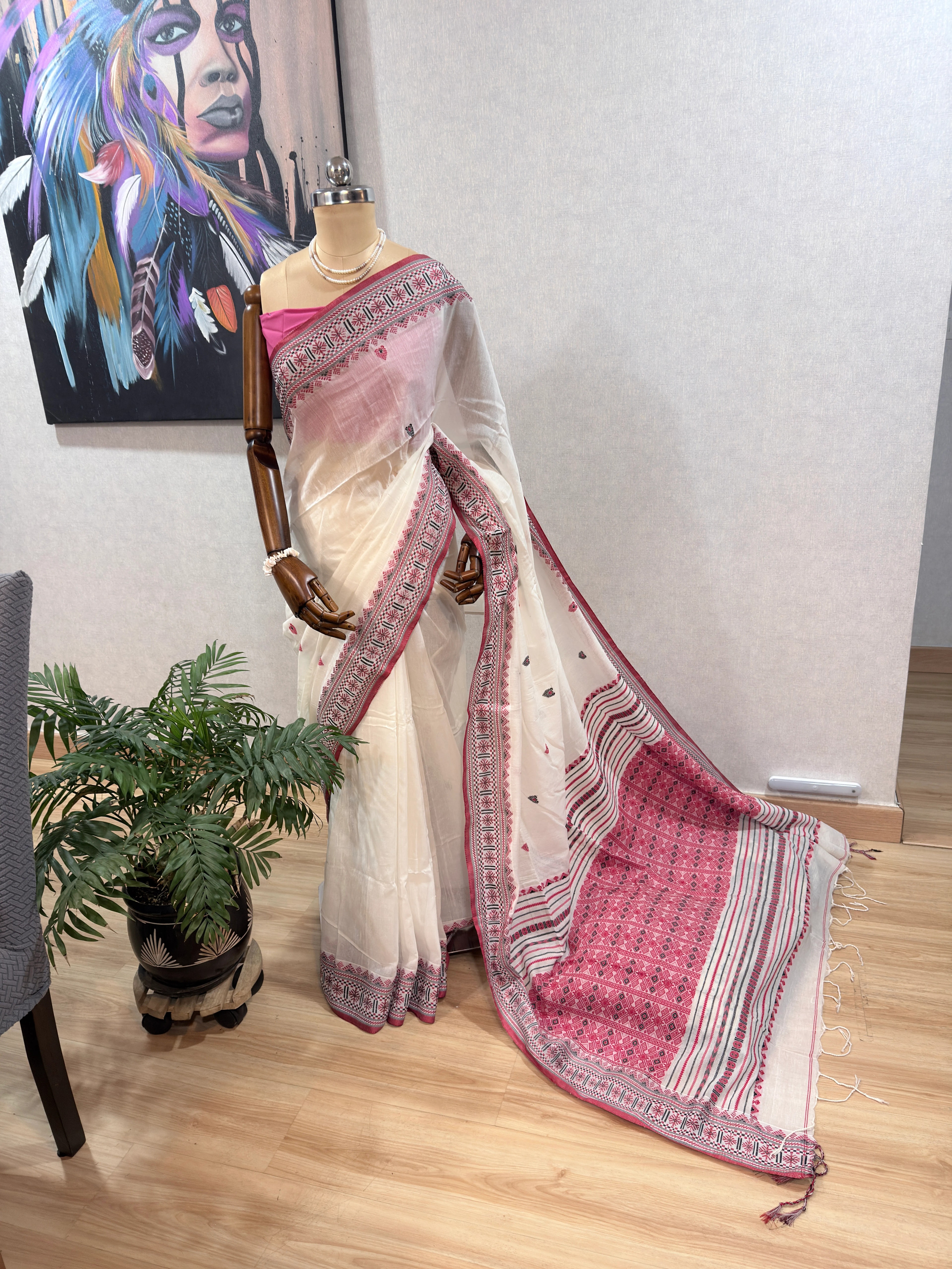 Close-up flat lay of the Dhonekhali saree's woven pink-and-black diamond border and striped end-piece with fringe.