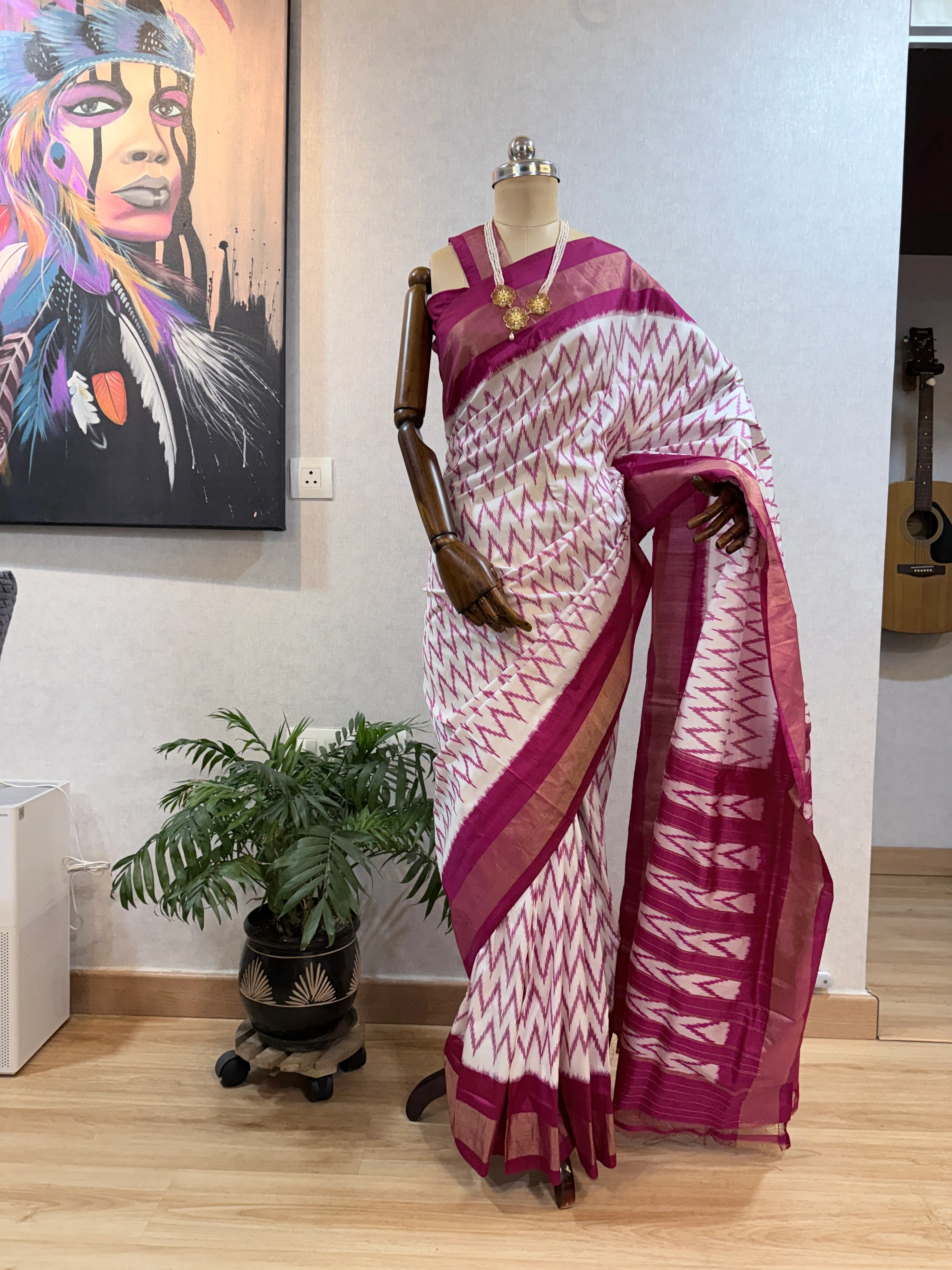 Maroon-and-white chevron ikat saree on the mannequin, close full-length view showing the pleats and heart-motif border band.